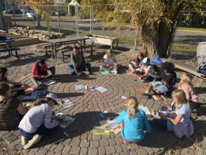 Youth grouped in a circle working on art project outside